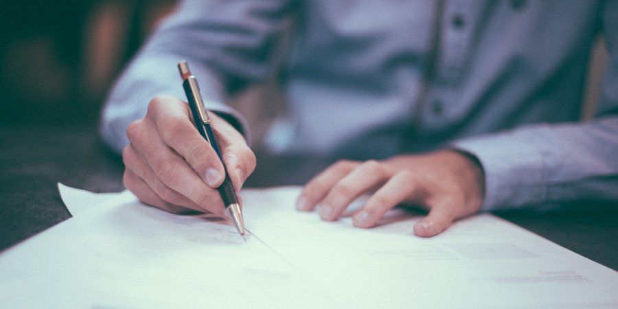 Homme signant un contrat d'assurance - New All Assistance pour l'analyse des contrats et les réclamations de polices privées
